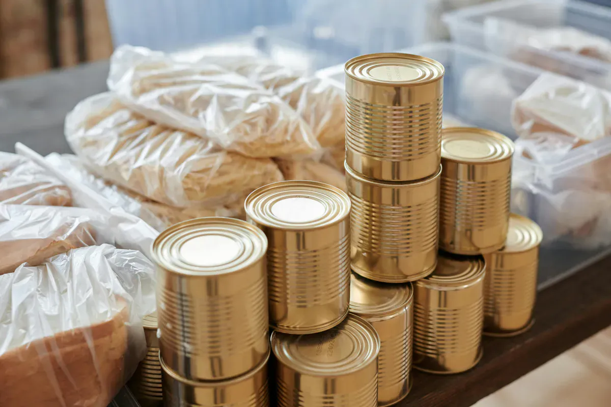 Stacked cans and packaged meals on a shelf as a long-term emergency food storage supply for prepping