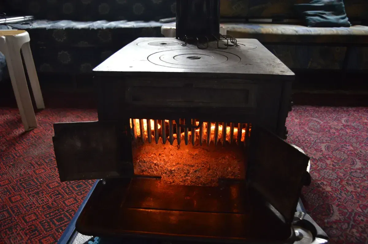 A vintage wood-burning heater radiating warmth inside a cozy off-grid cabin room during winter