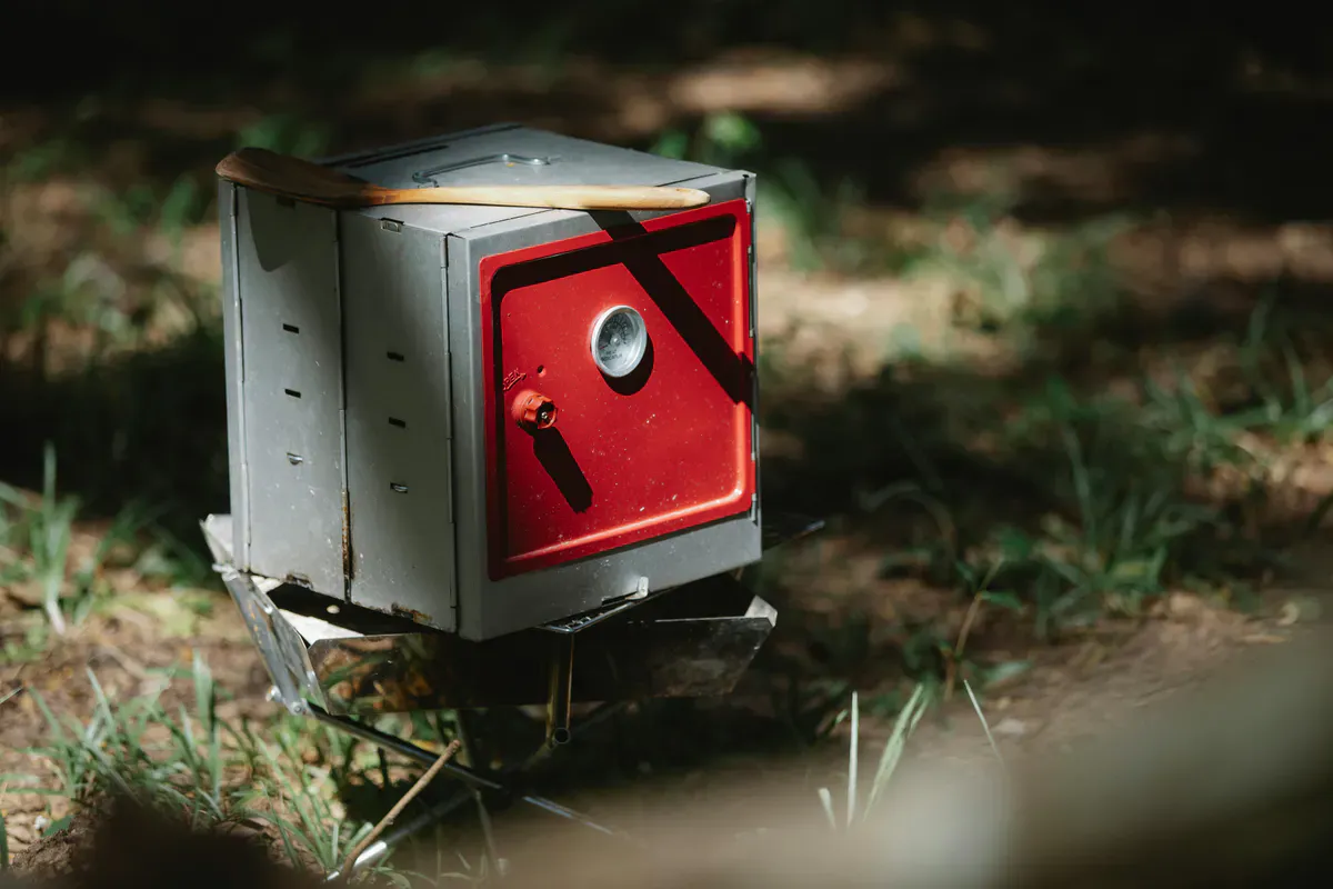 A small portable camp oven cooking outdoors in direct sunlight for off-grid solar cooking