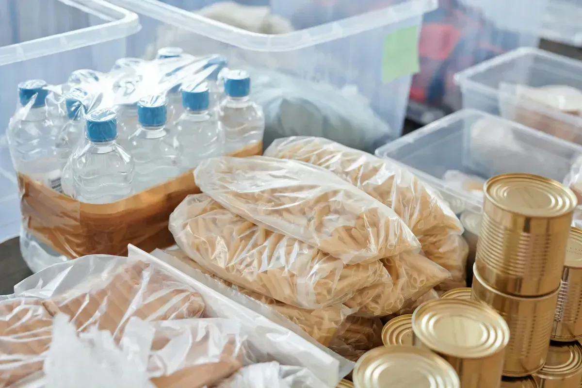 Bottled water and sealed food stored in containers on pantry shelves, an emergency water and supply reserve for off-grid living